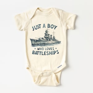 May include: A cream-coloured baby onesie with a blue and white illustration of a battleship and the text "Just a boy who loves battleships".