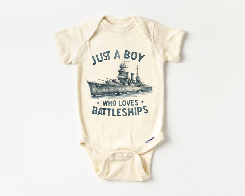 May include: A cream-coloured baby onesie with a blue and white illustration of a battleship and the text "Just a boy who loves battleships".