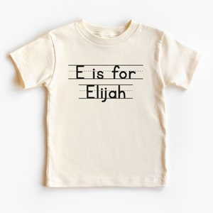 La carta personalizada es para la camisa de los niños con nombre, la camiseta personalizada con el nombre del niño, el traje de regreso a la escuela, la ropa para niños pequeños