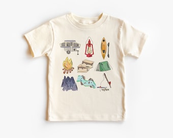 May include: A cream-colored t-shirt with a variety of camping-themed illustrations, including a camper, a tent, a campfire, a lantern, a kayak, a fishing rod, and mountains.