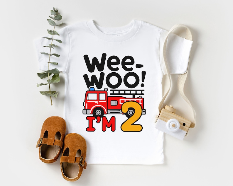 May include: White t-shirt with a red fire truck and the text "Wee-Woo! I'm 2" in black and yellow.