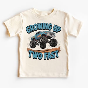 Könnte beinhalten: Cremefarbenes Kinder-T-Shirt mit einem blauen Monster-Truck-Motiv. Der Text "GROWING UP TWO FAST" ist in Blau und Schwarz gehalten. Das T-Shirt besteht aus weichem Material.
