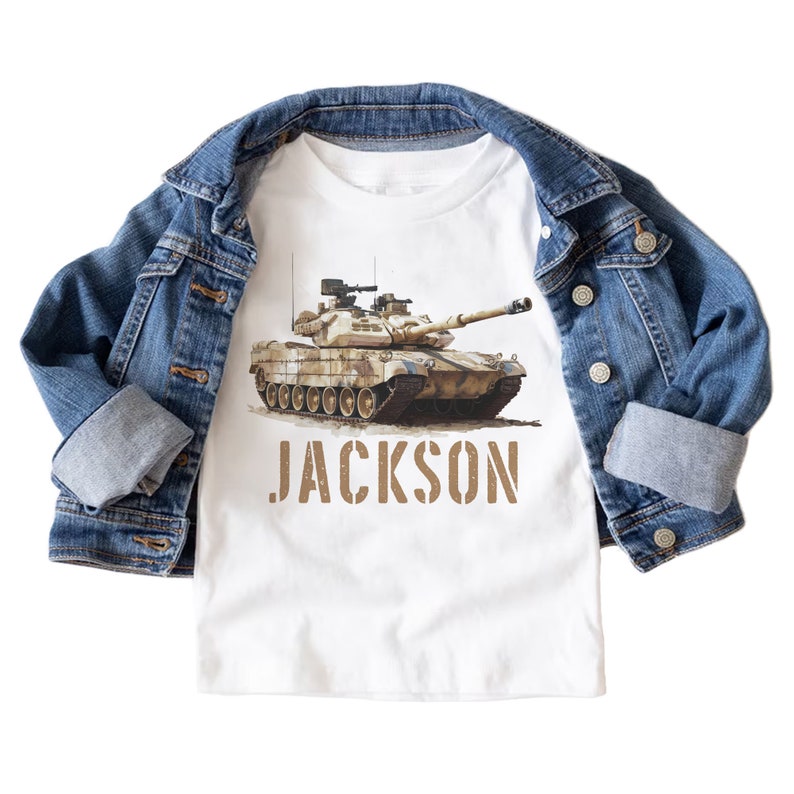 May include: White t-shirt with a brown camouflage tank printed on the front. The tank is facing the right side of the image. The name "JACKSON" is printed in brown below the tank.