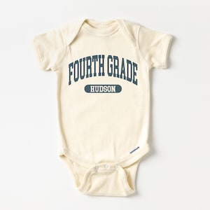May include: Cream-colored baby bodysuit with the text "FOURTH GRADE" in navy blue arched lettering. Below the text is the name "HUDSON" in a navy blue rectangle. The bodysuit has short sleeves and a snap closure.