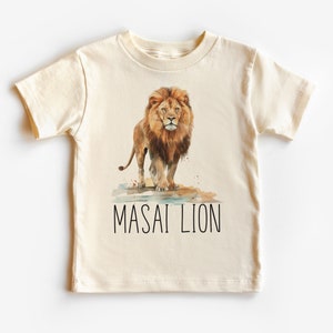 May include: A cream colored t-shirt with a watercolor illustration of a lion with the text "MASAI LION" printed below the image.