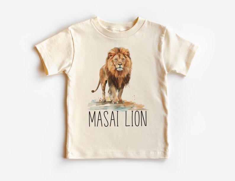 May include: A cream colored t-shirt with a watercolor illustration of a lion with the text "MASAI LION" printed below the image.