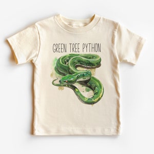 May include: A cream-coloured t-shirt with a detailed illustration of a green tree python. The snake has vibrant green scales and a yellow underbelly. The text "GREEN TREE PYTHON" is printed above the snake in black.