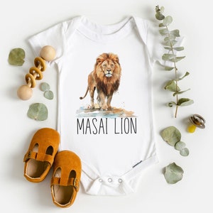 May include: White baby onesie with a watercolor illustration of a lion with the text "MASAI LION" printed below.
