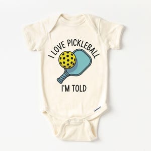 I Love Pickleball Im Told Baby Onesie® - Cute Funny Sports Pregnancy Reveal Birth Announcement Bodysuit - Pickleball Lover Natural Onesie®