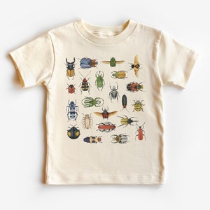 May include: A cream-colored t-shirt with a colorful pattern of various beetles. The beetles are illustrated in a vintage style with intricate details.
