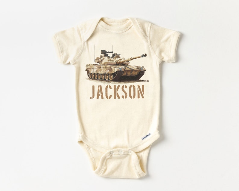 May include: A beige baby onesie with a camouflage tank printed on the front. The onesie has the name "JACKSON" printed in brown below the tank.