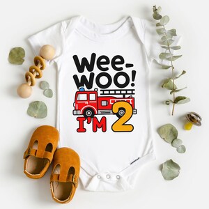 May include: White baby onesie with a red fire truck and the text "Wee-Woo! I'm 2".