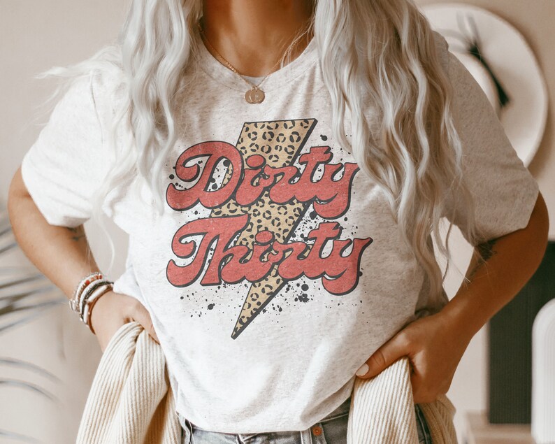 May include: A white t-shirt with a red and black graphic that says "Dirty Thirty" with a leopard print lightning bolt.