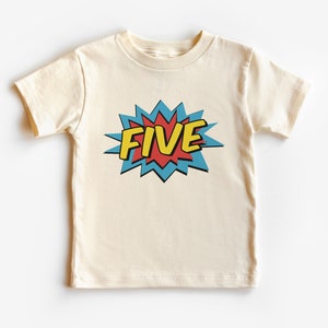 Può includere: Una maglietta color crema con una grafica in stile fumetto rosso, blu e giallo che dice "FIVE".