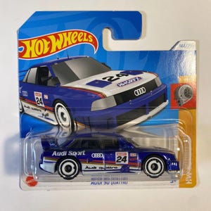 May include: A blue and white Hot Wheels die-cast toy car, a 1991 Audi 90 Quattro IMSA GTO, with the text "Audi Sport" and "Audi quattro" on the side. The car has a black interior and black wheels with white rims. The car has a number "24" on the side and the text "H&R" on the roof.