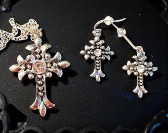 Conjunto de collar y pendientes con cruz gótica ornamentada en acero inoxidable plateado.