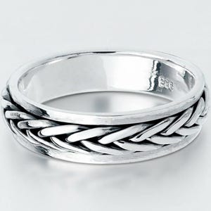 Puede incluir: Un anillo de plata con un diseño de banda trenzada. El anillo tiene un acabado pulido y un patrón tejido texturizado alrededor de la banda. El anillo probablemente está hecho de plata de ley y es adecuado para el uso diario.