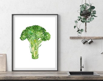 May include: A watercolor painting of a single broccoli floret with green leaves and a white stem. The painting is framed in a black frame and is hanging on a white wall.