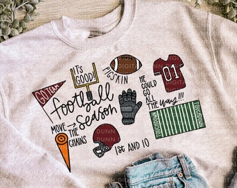 May include: A gray sweatshirt with a football theme. The design includes the words "Go Team", "It's Good!" "Pigskin", "He Could Go All The Way!!!", "Move The Chains", "Dunn Dunn", "Touchdown", and "1st and 10".
