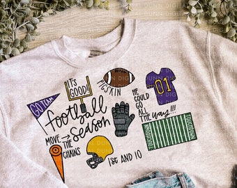 May include: A gray sweatshirt with a football theme. It features the text "Go Team, It's Good! Football Season" with various football-related illustrations, including a football, a helmet, a jersey, and a football field.