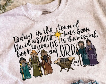 May include: A gray sweatshirt with a Christmas-themed design featuring a manger scene with three wise men and the text "Today in the town of David a SAVIOR has been born to you: HE is the messiah the LORD!" and "LUKE 2:11".