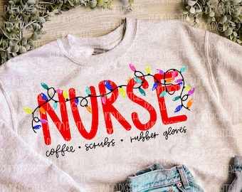 May include: A gray sweatshirt with the word "NURSE" in red letters surrounded by colorful Christmas lights. The text "coffee - scrubs - rubber gloves" is written below the word "NURSE". A pair of blue jeans and brown sandals are also in the image.
