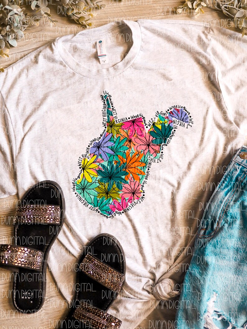 K&ouml;nnte beinhalten: Ein wei&szlig;es T-Shirt mit einem floralen Design des Bundesstaates West Virginia. Das Design enth&auml;lt die Worte "West Virginia", die sich um den Umriss des Bundesstaates wiederholen.