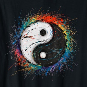 Op de afbeelding: Zwart T-shirt met een kleurrijk yin yang symbool ontwerp. Het symbool is omgeven door kleurrijke verfspatten.