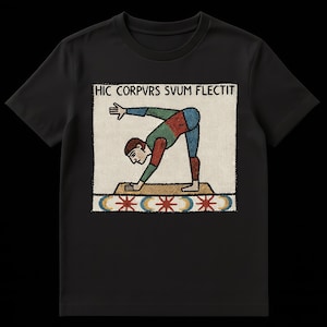 May include: Black t-shirt featuring a colorful illustration of a person bending over, with the Latin text "HIC CORPVS SVUM FLECTIT" above the image. The illustration has red, green, and blue accents. The shirt is made of a soft material.