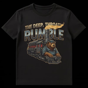 Può includere: T-shirt nera con un'illustrazione a cartoni animati di un orso che guida un treno. Il testo "THE DEEP, THROATY RUMBLE" è stampato sopra il treno. L'orso indossa un berretto blu e una tuta. Il treno è nero e grigio.