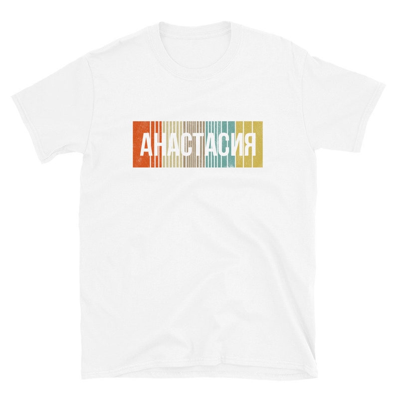 May include: White t-shirt with a vintage-style graphic of the word "Анастасия" in a colorful striped design.