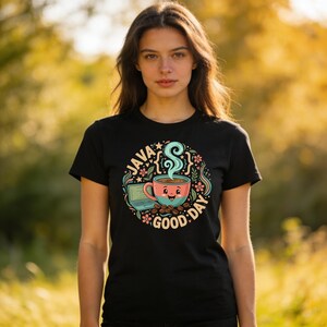 Peut inclure: T-shirt noir avec un motif circulaire. Le motif repr&eacute;sente une tasse de caf&eacute; fumante, un ordinateur portable et les mots "JAVA GOOD DAY". Le motif comprend des fleurs et des grains de caf&eacute;.