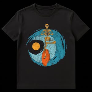 Op de afbeelding: Zwart t-shirt met een surfend skeletontwerp. Het skelet staat in een yogahouding, met een blauw en oranje golfontwerp op de achtergrond. De zon is oranje. Het ontwerp is gedrukt op de voorkant van het shirt.