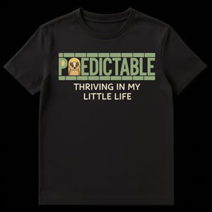 Może przedstawiać: Czarny t-shirt z zielonym napisem "Predictable" i ilustracją leniwca. Poniżej napis "Thriving in my little life". Koszulka wykonana jest z miękkiego materiału.
