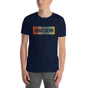 May include: A navy blue t-shirt with a retro-style graphic of the word "Анастасия" in a colorful striped design.