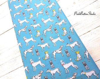 May include: A blue fabric with a repeating pattern of black and white dalmatian dogs, poodles, and other dog breeds. The dogs are all wearing collars and some have hats. The fabric is ideal for quilting, sewing, and crafting.