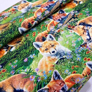 May include: A colorful fabric with a repeating pattern of foxes sleeping in a field of flowers. The foxes are orange and white with black noses and eyes. The flowers are red, yellow, blue, and purple. The background is green.