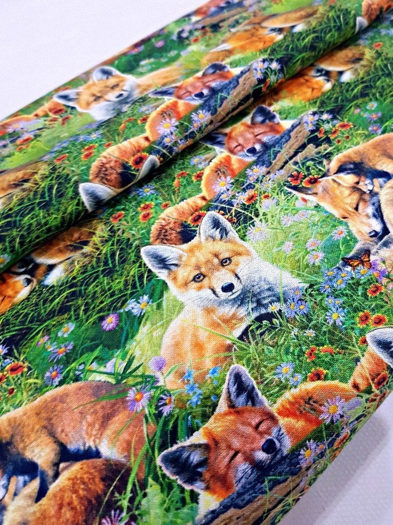 May include: A colorful fabric with a repeating pattern of foxes sleeping in a field of flowers. The foxes are orange and white with black noses and eyes. The flowers are red, yellow, blue, and purple. The background is green.