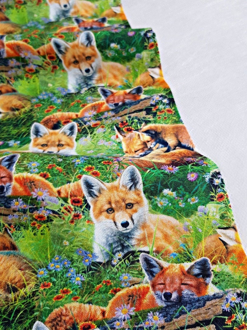 May include: A repeating pattern of red foxes in a green field with orange, blue, and white flowers. The foxes are in various poses, some are sleeping, some are sitting, and some are looking at the viewer.