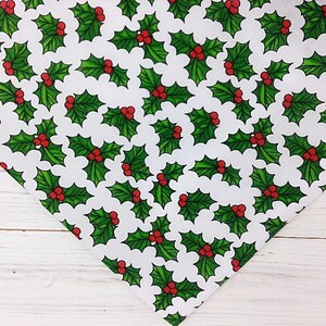 May include: White fabric with a repeating pattern of green holly leaves and red berries.