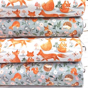 May include: Four rolls of fabric with a repeating pattern of foxes, mushrooms, and flowers. The fabric is in shades of blue, white, and orange.