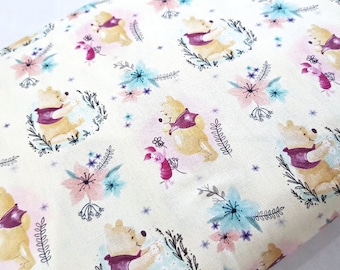 May include: White fabric with a repeating pattern of Winnie the Pooh and Piglet characters. The characters are depicted in a watercolor style with pink, blue, and purple floral accents.