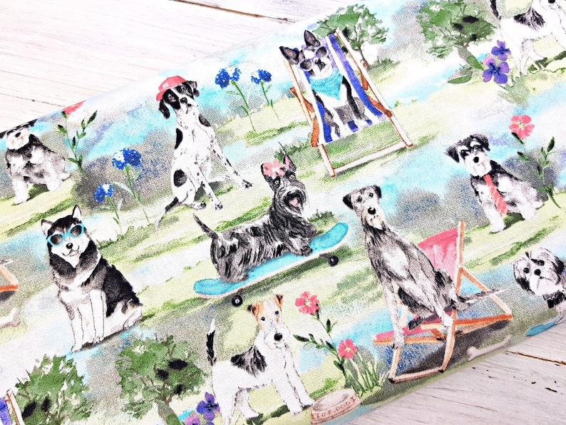 May include: Fabric with a whimsical print featuring various dog breeds in a park setting. Dogs are depicted wearing sunglasses, hats, and relaxing on beach chairs. The design includes flowers, trees, and a light blue and green color scheme.