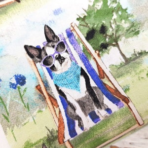 May include: A fabric with a watercolor illustration of a dog relaxing in a beach chair. The dog wears sunglasses and a blue bandana. The background features a green lawn, blue flowers, and trees.