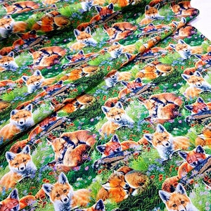 May include: A green fabric with a repeating pattern of red foxes sleeping in a field of green grass and colorful flowers.