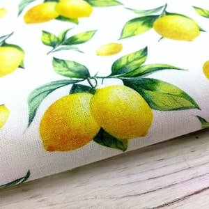 May include: White fabric with a repeating pattern of yellow lemons and green leaves. The lemons are painted in a watercolor style.