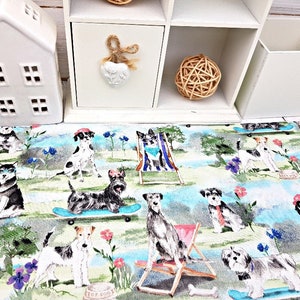 May include: A colorful fabric featuring various dog breeds enjoying leisure activities. Dogs are depicted on skateboards, in beach chairs, and in a park setting with flowers and trees. The fabric has a light blue and green background.