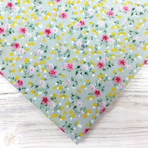 May include: A light green fabric with a small floral print. The print features pink and yellow flowers on a light green background.