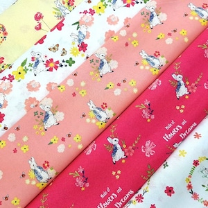 Puede incluir: Cuatro paneles de tela con un patrón floral y de conejito. Los paneles son en tonos de rosa, amarillo y blanco. El texto "Made of Flowers and Dreams" está impreso en el panel rosa.