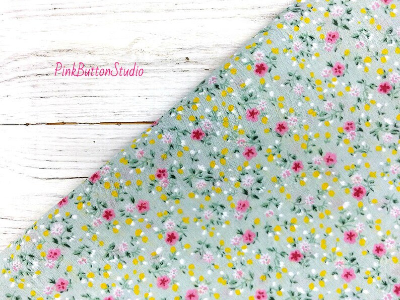 May include: A light green fabric with a small pink and yellow floral print. The fabric is a sheer, lightweight material.